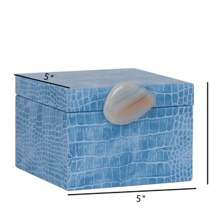 May include: A light blue square box with a crocodile-embossed pattern and a light pink agate stone lid. The box measures 5 inches by 5 inches by 3.9 inches.