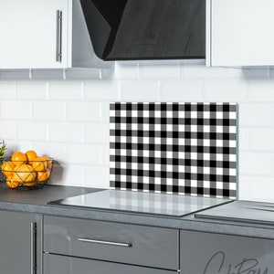 May include: Black and white checkered kitchen backsplash with a white countertop and gray cabinets. The backsplash is made of tempered glass and is heat resistant.