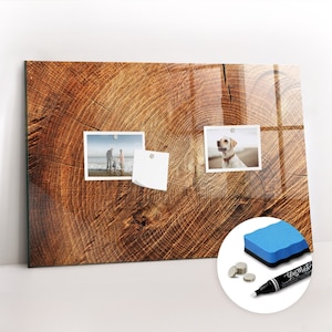 Könnte beinhalten: Ein magnetisches Glas-Trockenstift-Board mit Holzmaserung. Das Board hat zwei Fotos und einen Haftnotiz daran befestigt. Das Board wird mit einem blauen Trocken-Stift, einem blauen Radiergummi und drei silbernen Magneten geliefert.