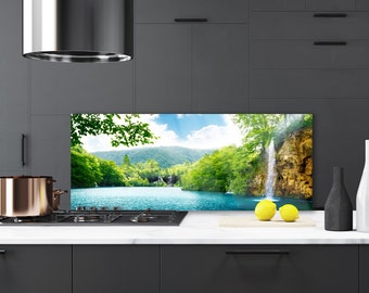 Puede incluir: Un protector de salpicaduras de cocina con una imagen escénica de una cascada y un lago rodeados de exuberantes árboles verdes. La imagen está impresa en un panel de vidrio transparente y está instalada detrás de una estufa de gas.
