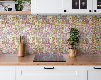 May include: A kitchen backsplash featuring a repeating pattern of colorful cartoon desserts including donuts, cupcakes, macarons, and slices of cake with smiling faces in shades of pink, yellow, blue, and brown, set against white cabinets.