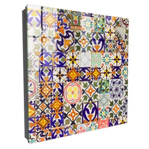 Può includere: Un'opera d'arte murale quadrata composta da un collage di varie piastrelle in ceramica con motivi complessi nei toni del blu, arancione, giallo, verde e bianco. Le piastrelle sono disposte a griglia, creando un mosaico vivace e colorato.