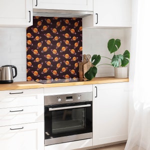 May include: A kitchen backsplash with a repeating pattern of orange planets with rings on a dark brown background.