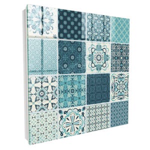 Può includere: Un pannello da parete quadrato con una griglia di sedici piastrelle in varie tonalità di blu, verde acqua e bianco. Ogni piastrella presenta un motivo geometrico o floreale distinto, creando un design a mosaico coeso con finitura lucida.