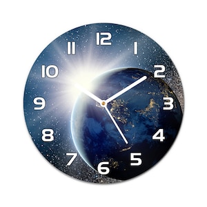Può includere: Un orologio rotondo con un'immagine blu e bianca della Terra e delle stelle. Il quadrante dell'orologio ha numeri e lancette bianchi.