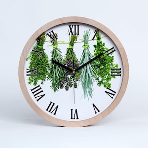 May include: A white clock with Roman numerals and a black hour hand and minute hand. The clock face features a design of four bunches of herbs hanging from a string.