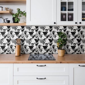 May include: Black and white geometric patterned kitchen backsplash with a black glass hob.