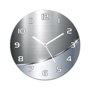 May include: A silver and grey round clock with white numbers and hands. The clock has a brushed metal finish and a subtle curve on the bottom half.
