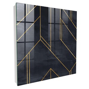 Può includere: Un pannello da parete quadrato con uno sfondo ad acquerello blu navy scuro e grigio antracite, sovrapposto a sottili linee dorate nitide e intersecanti che formano un motivo geometrico sulla superficie lucida e riflettente dell'oggetto.
