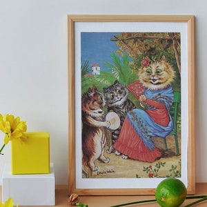 Op de afbeelding: Een ingelijste print van een schilderij van Louis Wain met drie katten gekleed in mensenkleding. De kat in het midden draagt een rode en blauwe jurk en houdt een waaier vast. De kat links speelt trommel. De kat rechts draagt een grijze en witte jurk. Het schilderij is gesitueerd in een tuin met een wit gebouw op de achtergrond.