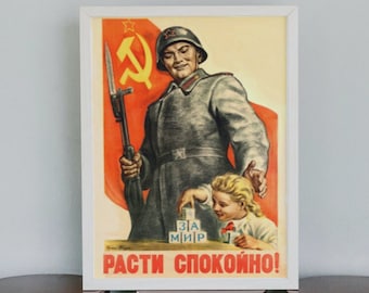 Può includere: Un manifesto di propaganda sovietica vintage in una cornice bianca. Il manifesto presenta un soldato in uniforme militare che tiene un fucile e un bambino piccolo che gioca con i blocchi di costruzione. Il manifesto dice "Cresci pacificamente!" in russo.