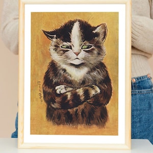 Peut inclure: Une estampe encadrée d'un chat noir et blanc aux yeux verts, assis les bras croisés. Le chat a une expression boudeuse sur son visage. L'arrière-plan est de couleur jaune-orange. L'estampe est signée "Louis Wain".