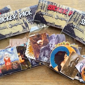 May include: A sticker pack with a variety of occult and celestial themed designs. The stickers are packaged in a clear plastic bag with a brown paper header card that reads "Sticker Pack Occult, Celestial & Cre".