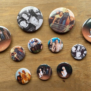 Pode incluir: Um conjunto de 11 botões redondos com fotos em preto e branco de uma banda. As fotos mostram os membros da banda em várias poses, incluindo em pé, sentados e posando em um carrinho de compras. Os botões são todos do mesmo tamanho e têm um fundo branco.