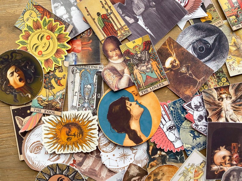May include: A collection of vintage tarot cards and stickers featuring various designs, including a sun, an eye, a skull, and a creature from the black lagoon. The cards are in a variety of colors, including red, blue, green, and yellow. The stickers are in a variety of colors, including black, white, and gold. The text on the cards includes "THE FOOL", "THE LOVERS", "THE HIGH PRIESTESS", and "CLES".