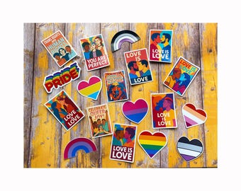 May include: A collection of colorful stickers and heart-shaped designs with LGBTQ+ themes. The stickers feature phrases like "Love is Love," "Pride," and "Trans Rights are Human Rights." The designs include rainbow, bisexual, pansexual, and lesbian pride symbols.