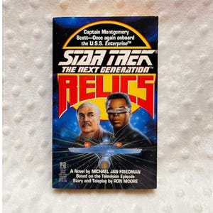 May include: A VHS tape for "Star Trek: The Next Generation - Relics." The cover features images of two men, a starship, and the title in bold red letters. The text includes "Captain Montgomery Scott" and "A Novel by Michael Jan Friedman."