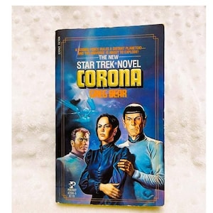 May include: A vintage paperback book cover featuring a Star Trek novel titled "Corona" by Greg Bear. The cover art depicts a futuristic scene with three characters, including Captain Kirk, against a blue and white background.