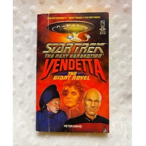 May include: A paperback book titled "Star Trek: The Next Generation: Vendetta" by Peter David. The cover features images of characters and the starship Enterprise against a red background. The book is a "Giant Novel".