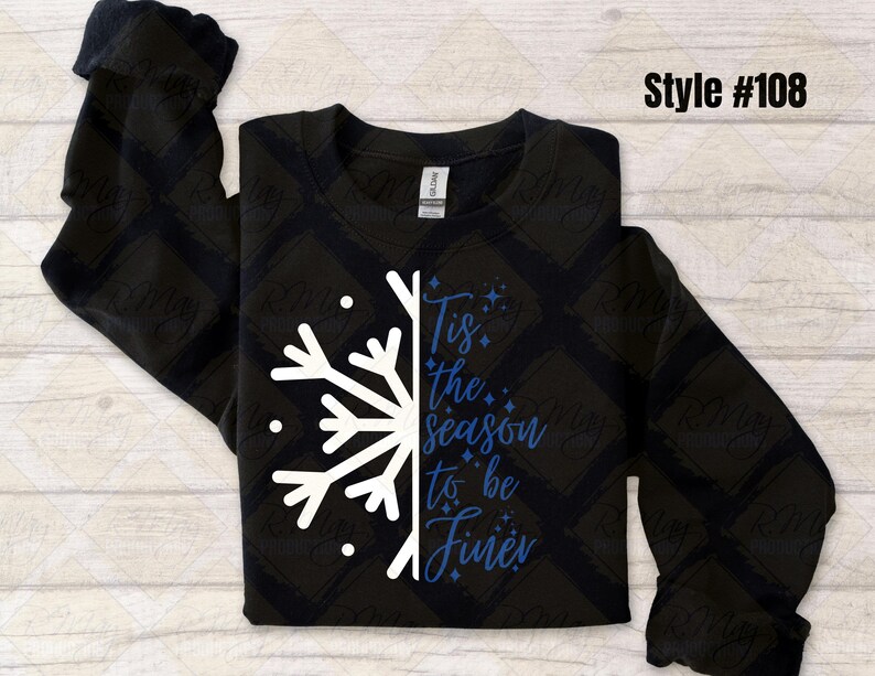 May include: Black sweatshirt with a white snowflake design on the left side and the phrase "Tis the season to be Finer" in blue script. The sweatshirt has long sleeves and a crew neck. Style #108 is printed in black.