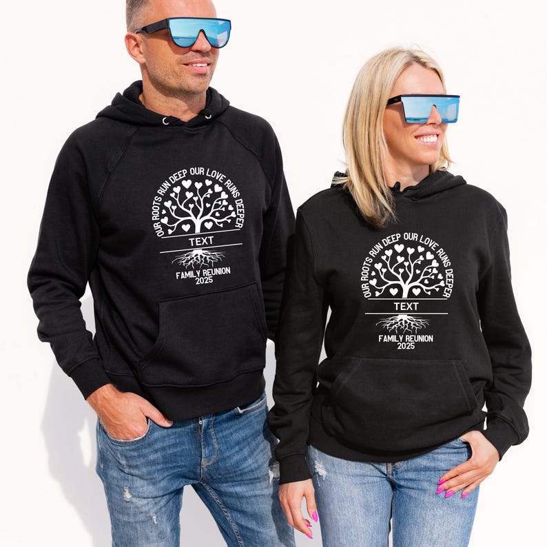Op de afbeelding: Zwarte hoodies met een wit boomontwerp en de tekst "Onze wortels lopen diep, onze liefde loopt dieper. Tekst Familie Re&uuml;nie 2025."