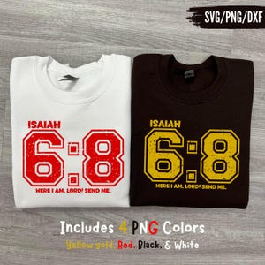 May include: Two sweatshirts, one white and one brown, with the text "ISAIAH 6:8" in a distressed font. The white sweatshirt has red text, and the brown sweatshirt has yellow text. The phrase "HERE I AM, LORD! SEND ME." is below the numbers.