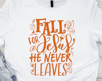 May include: Orange text on a white t-shirt reads "Fall for Jesus He Never Leaves" with fall-themed illustrations.