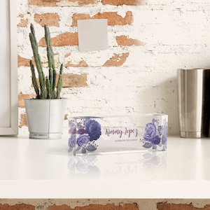 Peut inclure: Un presse-papier en verre transparent avec un motif floral et le texte "Kimmy Lopez Interior Designer".