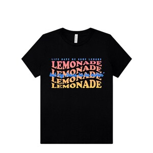 May include: Black crew neck t-shirt with the text "LIFE GAVE ME SORE LEMONS but my Jesus he be makin' LEMONADE" in a colorful, wavy font. The design features the word "LEMONADE" repeated multiple times in different colors.