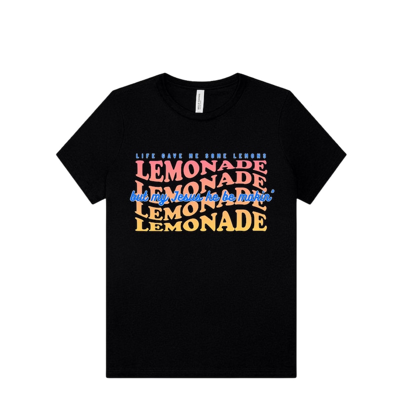 May include: Black crew neck t-shirt with the text "LIFE GAVE ME SORE LEMONS but my Jesus he be makin' LEMONADE" in a colorful, wavy font. The design features the word "LEMONADE" repeated multiple times in different colors.