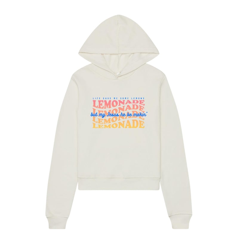May include: Cream-colored hoodie with a drawstring hood. The front features the text "LIFE GAVE ME SOME LEMONS, LEMONADE, but my Jesus he be makin' LEMONADE" in colorful, layered fonts. A casual, comfortable garment.
