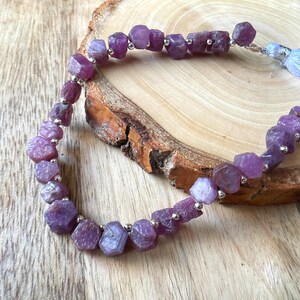May include: A strand of purple gemstone beads with silver spacers. The beads are faceted and have a rough, natural look.