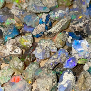 May include: A collection of rough opal stones in various shades of blue, green, and white. The stones are irregular in shape and have a natural, unpolished finish.