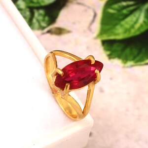 Puede incluir: Un anillo de oro con una gran piedra preciosa roja en forma de marquesa.