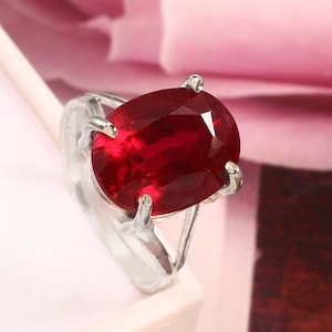 May include: A silver ring with a large, oval-shaped, red gemstone.