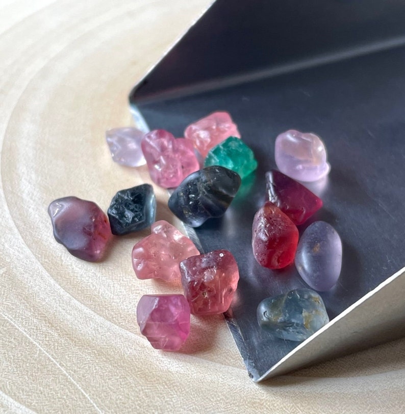 Puede incluir: Una colecci&oacute;n de piedras preciosas de colores, incluyendo rosa, rojo, verde y azul, se muestran en una pala de plata. Las piedras preciosas son de varias formas y tama&ntilde;os.