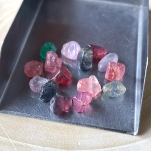 Puede incluir: Una colecci&oacute;n de peque&ntilde;as piedras preciosas facetadas en varios tonos de rosa, rojo, verde y azul. Las piedras preciosas est&aacute;n dispuestas en c&iacute;rculo sobre una bandeja plateada.