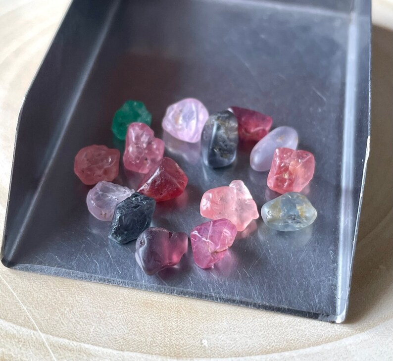 Puede incluir: Una colecci&oacute;n de peque&ntilde;as piedras preciosas facetadas en varios tonos de rosa, rojo, verde y azul. Las piedras preciosas est&aacute;n dispuestas en c&iacute;rculo sobre una bandeja plateada.