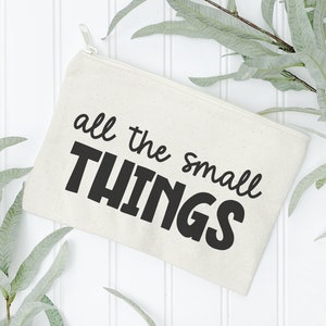 May include: A white canvas zippered pouch with the text "all the small THINGS" printed in black.
