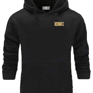 Könnte beinhalten: Schwarzer Kapuzenpullover mit Kängurutasche und Kordelzug. Der Pullover hat den goldenen Text "ICONIC" auf der Brust und ein kleines weißes Logo in der Nähe der Kapuze. Ein bequemes, lässiges Kleidungsstück.