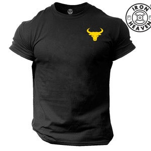 Könnte beinhalten: Schwarzes T-Shirt mit einem gelben Stierkopf-Logo auf der linken Brust. Das Logo ist ein stilisierter Stierkopf mit Hörnern und einem weißen Umriss. Der Text "IRON HEAVEN" befindet sich in einem Kreis über dem Stierkopf.