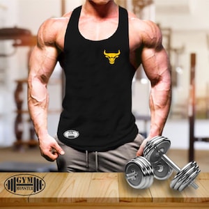 Puede incluir: Un tanque negro sin mangas con un logotipo de toro amarillo en la parte delantera. El tanque tiene el texto "GYM MONSTER" impreso en la parte inferior. El tanque está siendo usado por una persona con un físico musculoso. La persona está sosteniendo dos mancuernas plateadas.