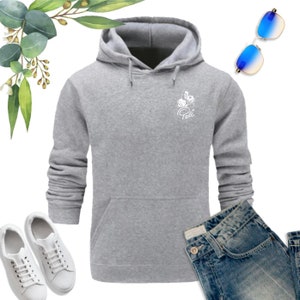 May include: A gray hooded sweatshirt with a white graphic of a flower and the word "Pelli" on the front. The sweatshirt has a kangaroo pocket and long sleeves.