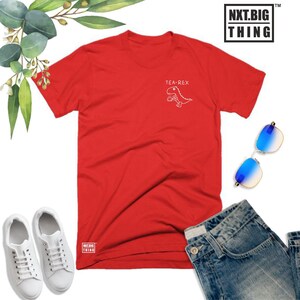 May include: Red t-shirt with a white graphic of a dinosaur holding a cup with the text "Tea-Rex".