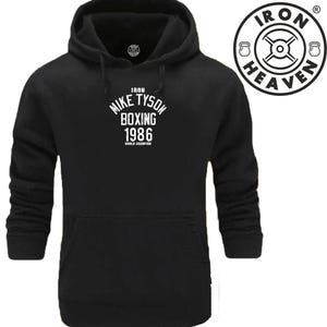 May include: Black hoodie featuring the text "Mike Tyson Boxing 1986 World Champion" in white. The hoodie has a drawstring hood and a front pocket. A circular logo with the words "Iron Heaven" is on the upper right.