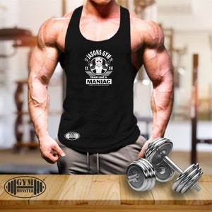 Puede incluir: Camiseta negra sin mangas con un estampado gráfico blanco de un hombre con una máscara de hockey y sosteniendo pesas. El texto gráfico dice "Jasons Gym" y "Train Like A Maniac".