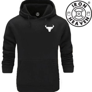 Op de afbeelding: Zwart hoodie met een wit stierenlogo op de voorkant. Het logo is een silhouet van een stierenkop met hoorns. De hoodie heeft een kangoeroezak en een capuchon met trekkoord. De tekst "IRON HEAVEN" is gedrukt in een cirkel met een halterstang en halters.