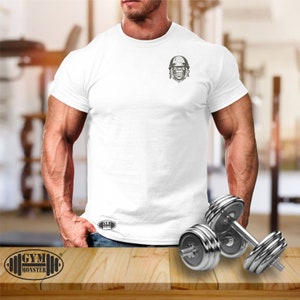 May include: White t-shirt with a small graphic of a gorilla wearing a helmet on the left chest. The text "GYM MONSTER" is printed on the bottom of the shirt.