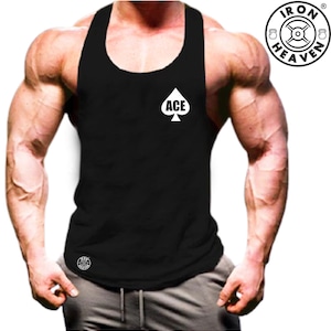 Puede incluir: Camiseta de tirantes negra sin mangas con una pica blanca y la palabra "ACE" impresa en la parte delantera. La camiseta tiene un cuello redondo y un ajuste holgado. El nombre de la marca "IRON HEAVEN" está impreso en un círculo blanco en el lado derecho de la camiseta.