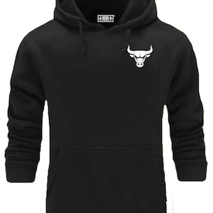Könnte beinhalten: Schwarzer Kapuzenpullover mit einem weißen Bullenlogo auf der Vorderseite. Das Logo ist ein stilisierter Bullenkopf mit Hörnern.